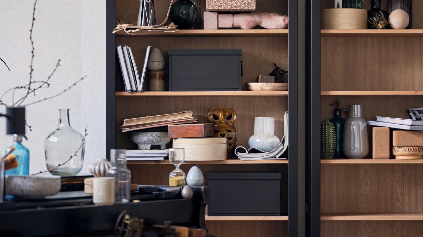 ארון HEMNES מלא בחפצי קרמיקה, ספרים, קופסאות אחסון ופריטים נוספים.