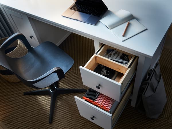 HEMNES 헴네스 책상의 원목 서랍이 열려 있고, 그 안에 칸막이로 분류된 서류, 전자기기, 필기용품이 보이는 모습.