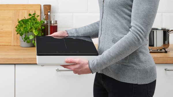 Henkilö pitelee TILLREDA-sarjan   kannettavaa keittotasoa.