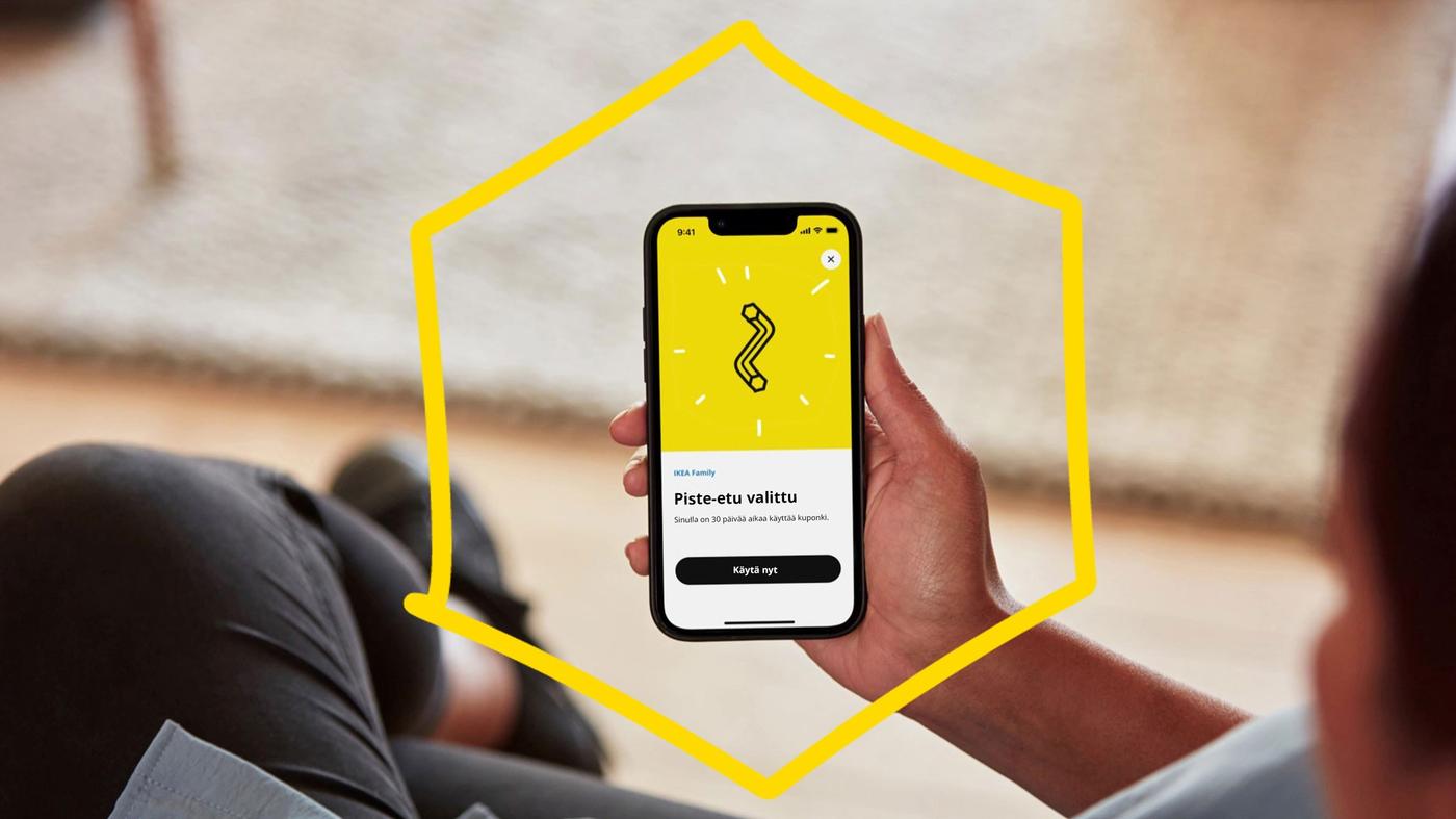 Henkilön kädessa älypuhelin ja näytössä kuva piste-etuohjelmasta.