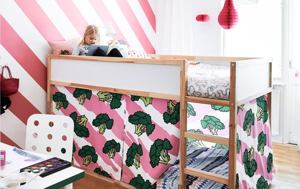 Henrik's daughter on her top bunk, reading a book against a white and bright pink striped wall in her redecorated bedroom.