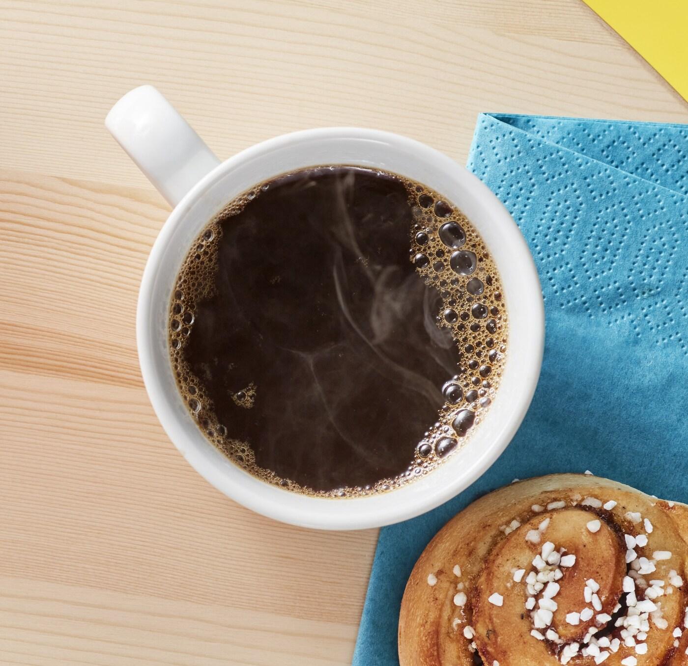  Herbata w kubku i cynamonka na niebieskiej serwetce.