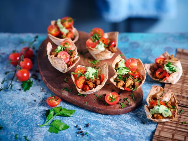 Herzhafte Tortilla Muffins mit Tomate & Avocado auf einem Holzbrett.