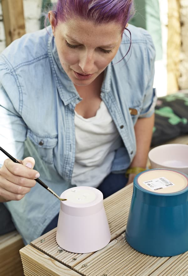 Hester paints glue on to the pots.