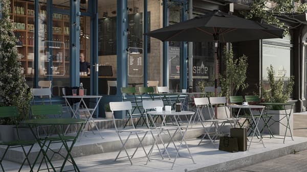 Het terras van een café met rijen grijze en groene SUNDSÖ stoelen en tafels die naar buiten gericht zijn. Aan één zijde staat een geopende parasol.