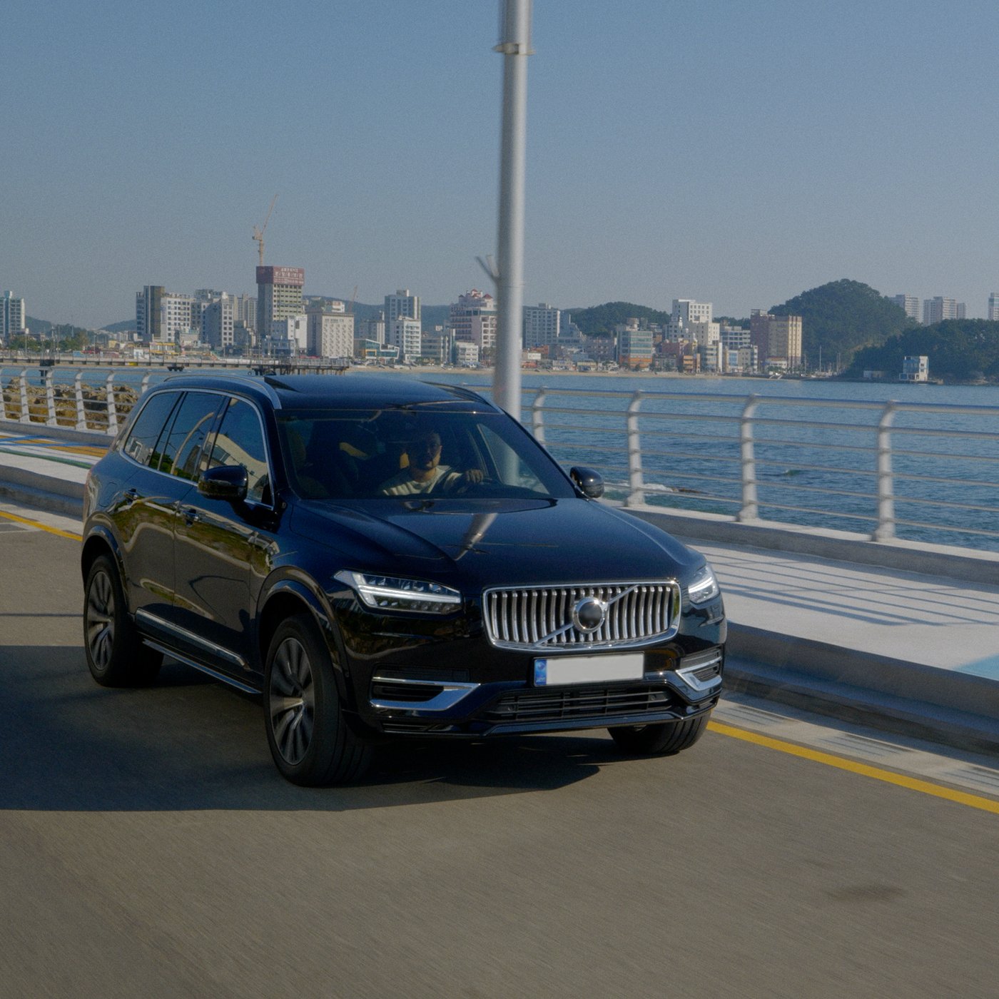 호숫가에 앉은 한 여성이 HETLEVRAD 헤틀레브라드 단열 플라스크에 담긴 뜨거운 음료를 마시고 있습니다.