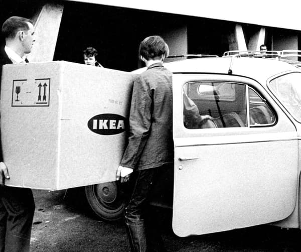 Historisk bild av män som försöker få in stort paket i liten bil