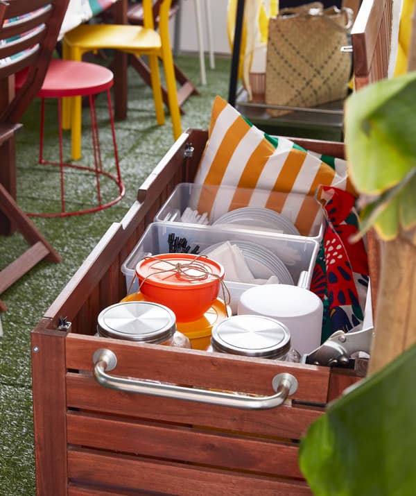 Hnedo morená úložná lavica IKEA ÄPPLARÖ vyrobená z dreva akácie naplnená doplnkami na oslavu.