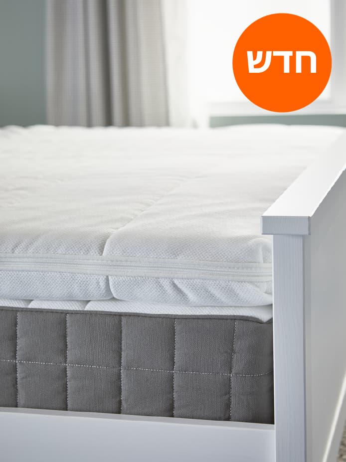 מיטה עם מזרן קפיצי כיס HÖVÅG ועליו רפידת מזרן TUSSÖY, עומדת ליד חלון בחדר שינה.