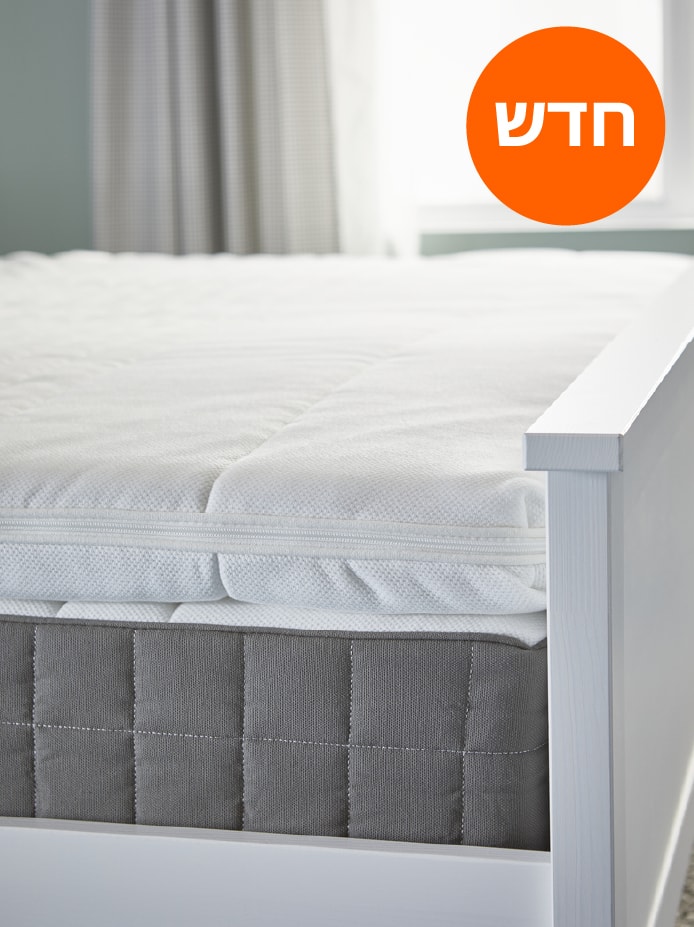 מיטה עם מזרן קפיצי כיס HÖVÅG ועליו רפידת מזרן TUSSÖY, עומדת ליד חלון בחדר שינה.