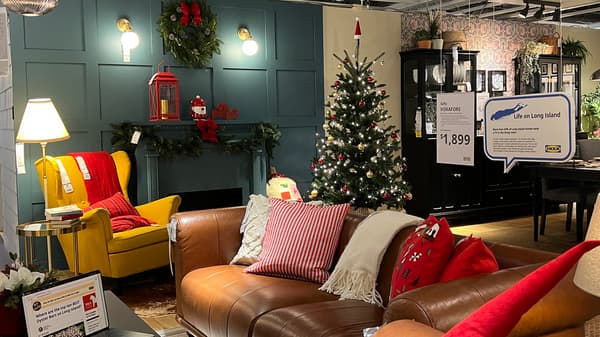 Holiday-themed living room display with leather sofa, yellow chair, Christmas tree, and festive decor.