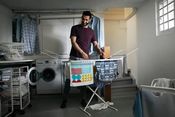 Hombre colgando paños de cocina recién lavador en el colgador blanco MULIG.