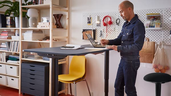 Hombre de pie junto a una mesa con una computadora
