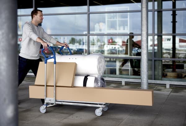 Hombre pasando con un carro lleno de cajas de cartón con compras de IKEA.