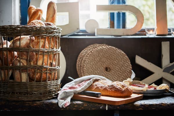 Homemade bread inside a rattan basket and a sliced loaf on the worktop