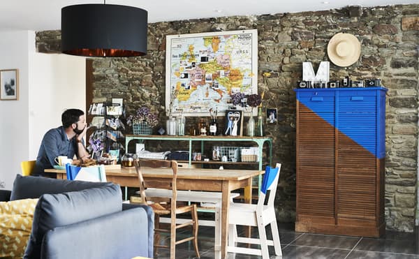 Homme assis à une table de salle à manger et mobilier peint.