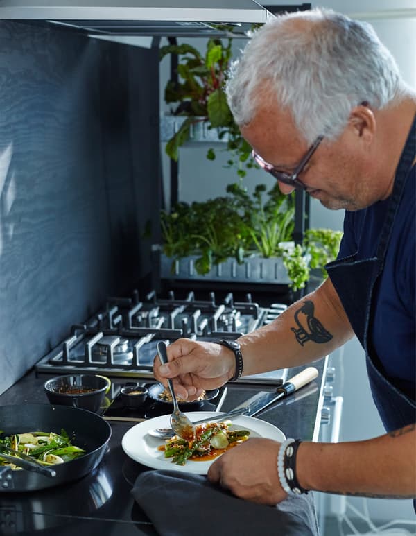 Homme en train de servir une assiette de salade.