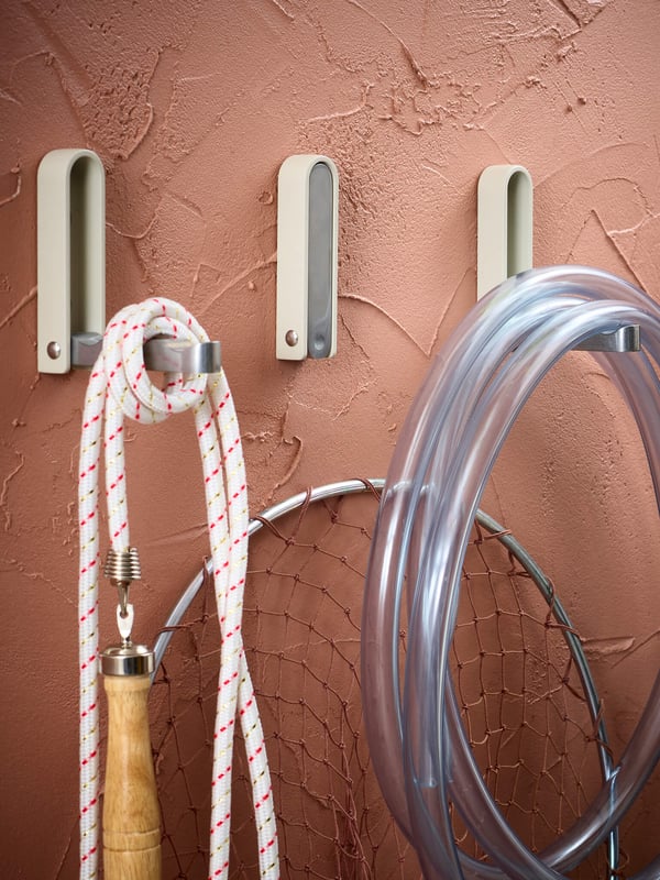 Hooks mounted on a wall with a jump rope and some tubing hanging from it.