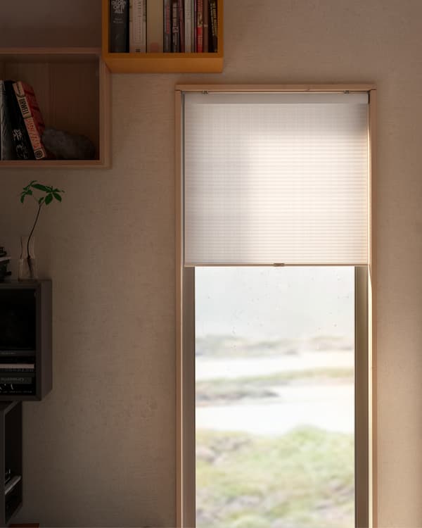 HOPPVALS white cellular blind with an insulation creating structure, almost open, in front of a window with an outdoors view.