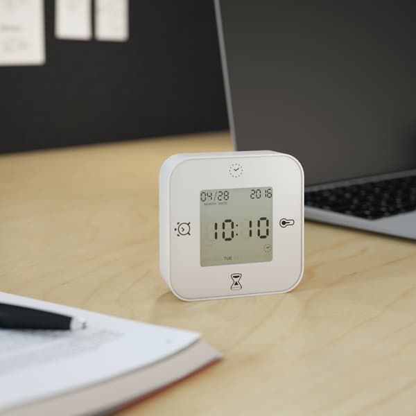 Horloge et thermomètre blanc posé à côté d'un ordinateur