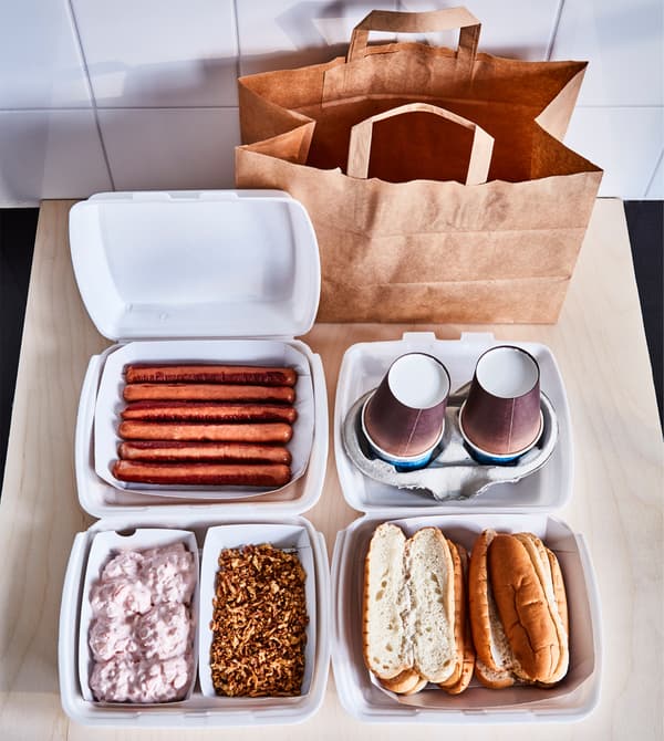 Hotdogs, buns, toppings and cups are laid out on a countertop.