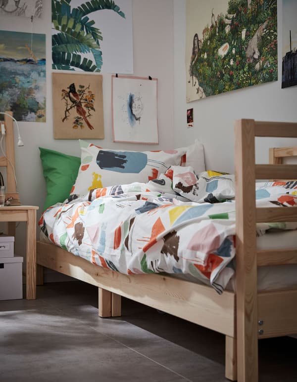 Housse de couette et taies d’oreiller DOFTKLINT sur un lit en bois dans une chambre d’étudiant.