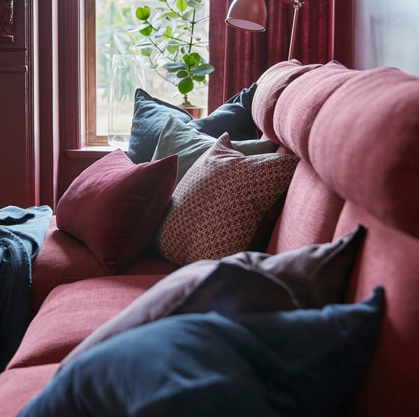 Housses de coussins SANELA bleu foncé et rouge foncé sur un canapé LIDHULT rouge-brun