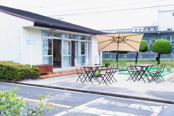 ホールから外へと続くコンクリート舗装されたエリアにはウッドパネルを敷き、屋外用のチェアとテーブル、パラソル、ベンチを置いてテラススペースを設置。