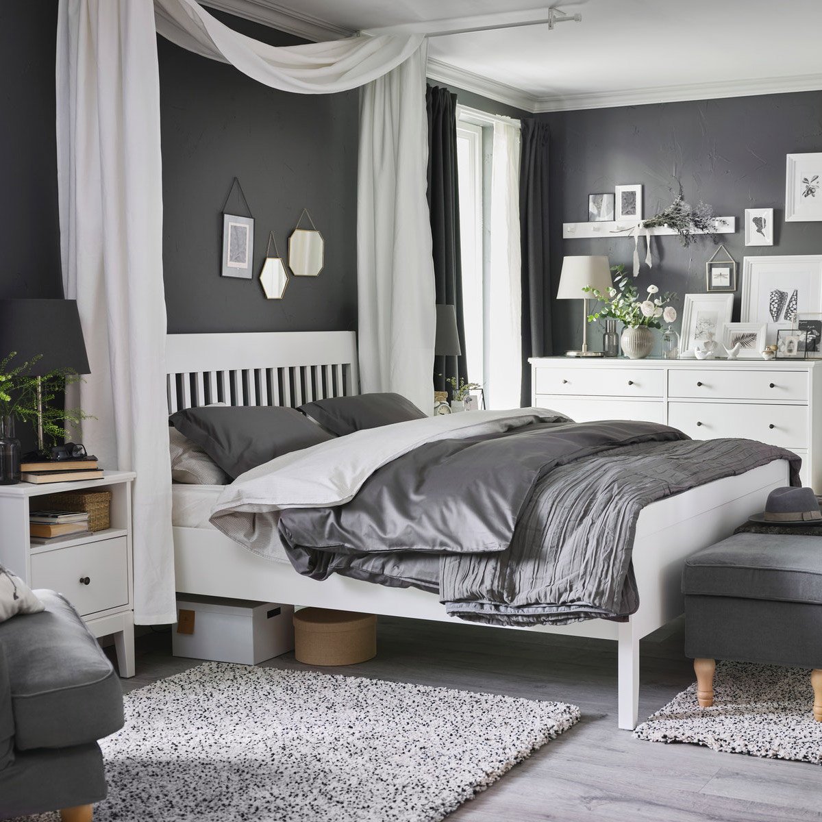 Hvid IDANÄS seng, sengebord og kommode står i et soveværelse med LUKTJASMIN sengesæt på sengen.