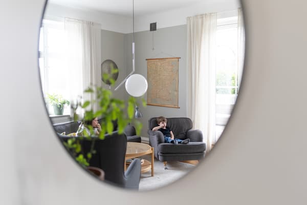 I en spegel ses två barn sitta i varsin fåtölj och titta på tv. 