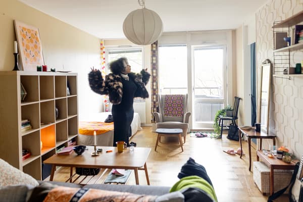 I ett vardagsrum i en lägenhet står en person mitt i rummet med utsträckta armar och ser nästan ut att dansa.