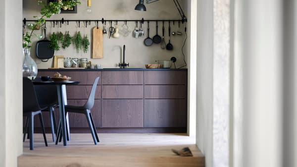 I mobili da cucina in legno scuro coprono la parte inferiore della parete della cucina. Sopra di essi sono appesi gli utensili da cucina.