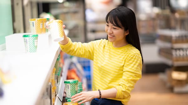 黄色いボーダーのトップスの人物がカップを並べるイケアストアの売場と商品ディスプレイ