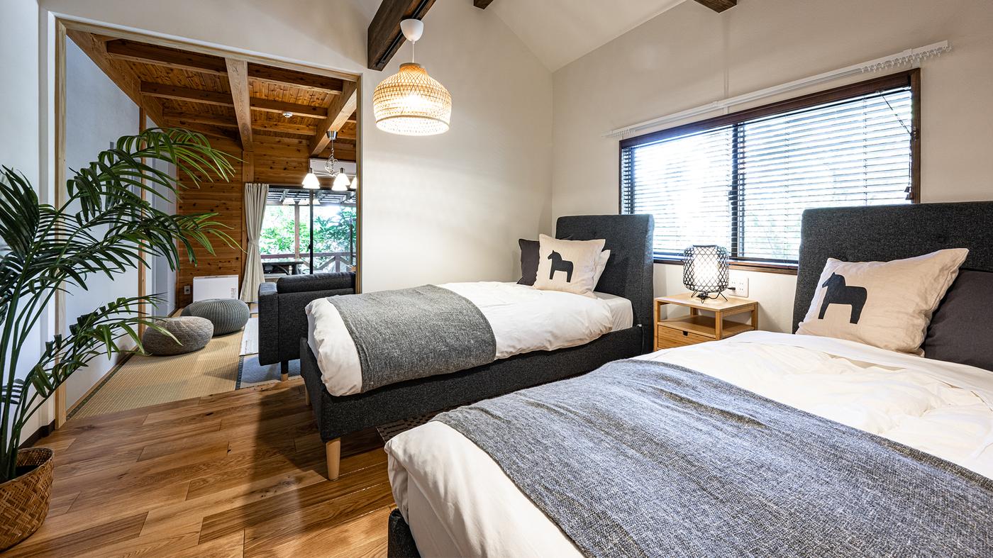 黒いベッドが2つ並んでいる。馬の絵の枕とグレーのベッドカバーがかかっている。観葉植物が置いてある。