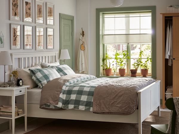 白いベッドにグリーンチェックの寝具を合わせたナチュラル寝室。窓辺の光で明るい雰囲気。