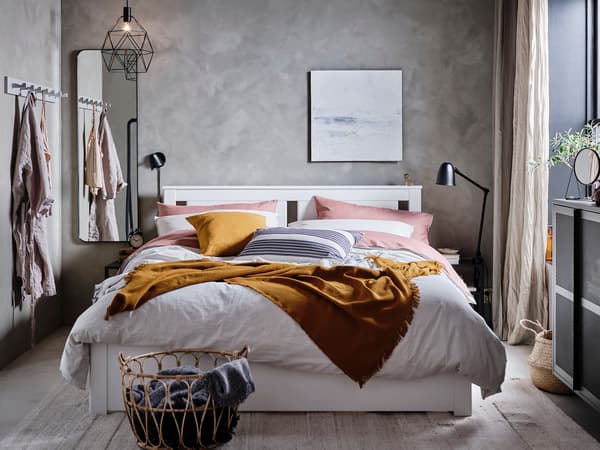白いベッドにキャメル色のブランケットを合わせたナチュラル寝室。グレーの壁と木製家具で温かみをプラス。