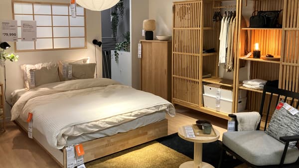低い木製ベッドとベージュの寝具が配置された北欧モダンな寝室。和紙ランタンが照らし、障子と家具が調和するショールーム
