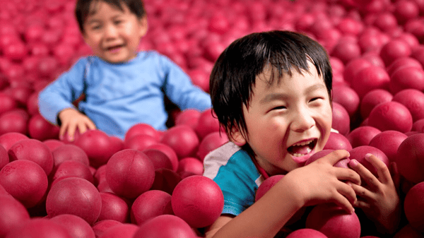 赤いボールが敷き詰められたボールプールで遊ぶ子どもたち。