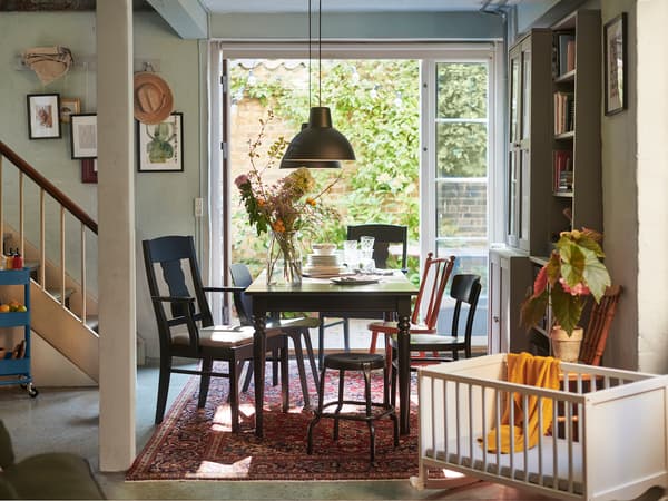 黒いダイニングチェアと木製テーブルを組み合わせたヴィンテージ風食卓。ラグと観葉植物で落ち着いた雰囲気。