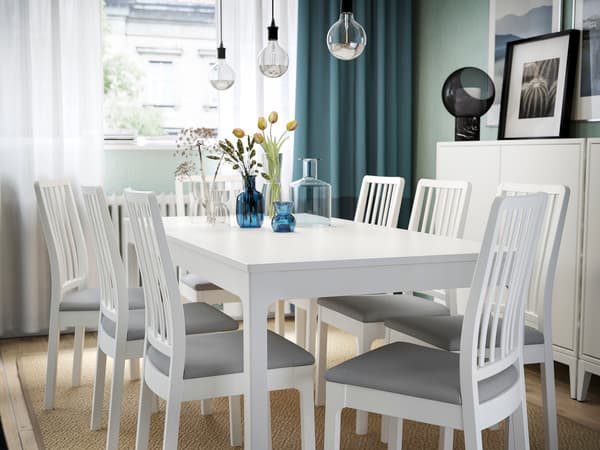 白いダイニングテーブルとチェアを並べた明るい食卓。窓辺の自然光で開放感のある空間。