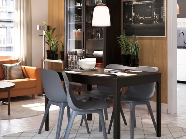 黒いダイニングテーブルとグレーの椅子を組み合わせたシックな食卓。木製パネルとペンダントライトが特徴。