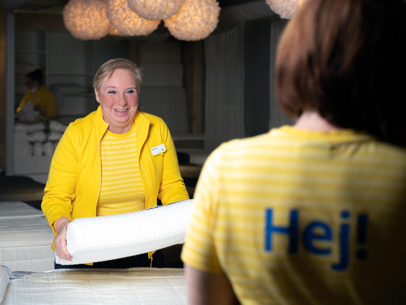 Idősebb IKEA munkatárs a hálószoba részlegen egy párnát helyez el.