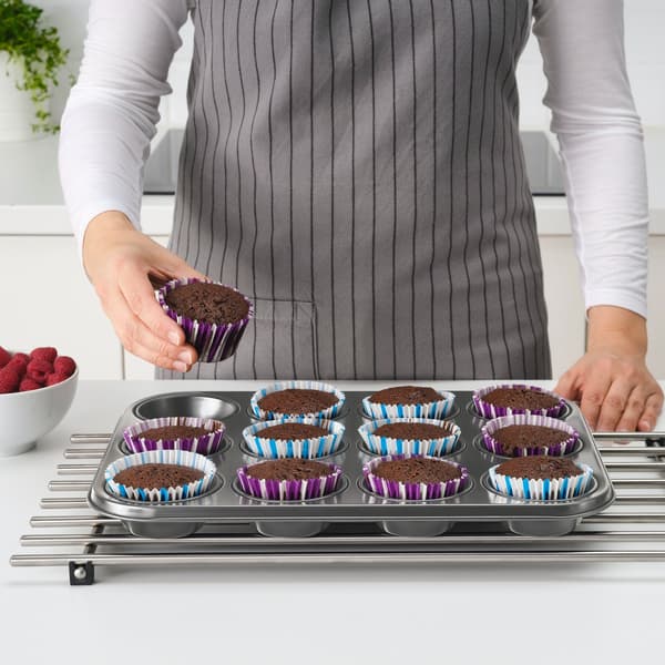 Iemand pakt een chocolademuffin uit het gevulde muffin bakblik.