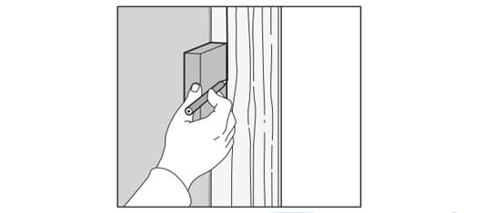 Iemand tekent een plek op een houten opvulstuk af.