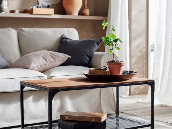 黒いフレームに木製天板のコーヒーテーブルを置いたモダンリビング。観葉植物でアクセント。