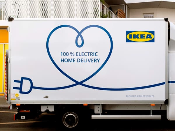 한 아파트 건물 옆에 주차되어 있는 흰색의 IKEA 100% 전기구동 가정배송 트럭.