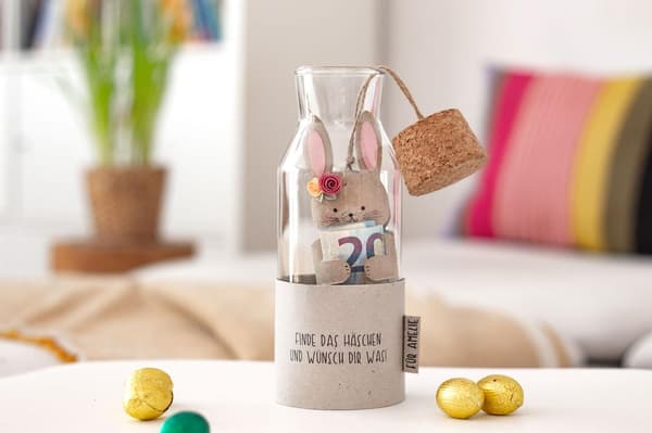 IKEA 365+ Karaffe mit einem kleinen Papphasen, der einen Geldschein hält, gestaltet.