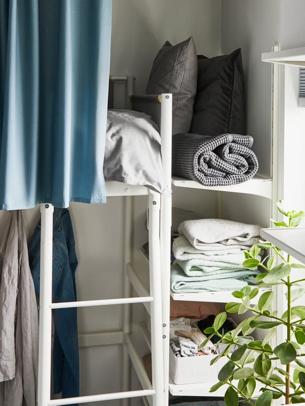 IKEA ALGOT wall shelving unit storing pillows and bedding next to a bunk bed.