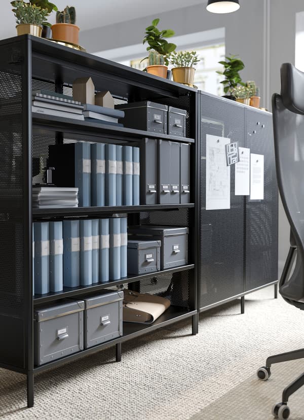 IKEA BEKANT zwarte rekken gebruikt om werkplekken van elkaar te scheiden met notitieblaadjes aan de magnetische panelen.