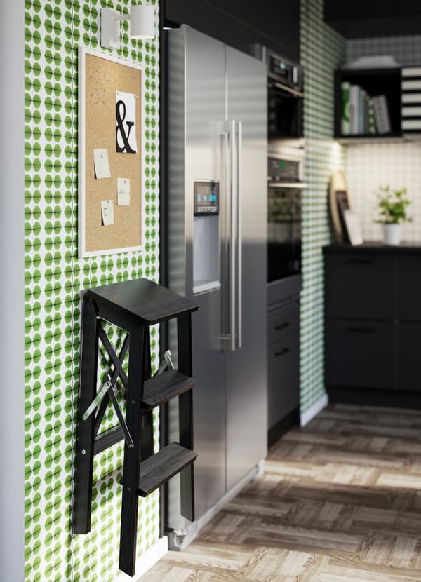 IKEA BEKVÄM foldable black three-step stepladder mounted to the wall.